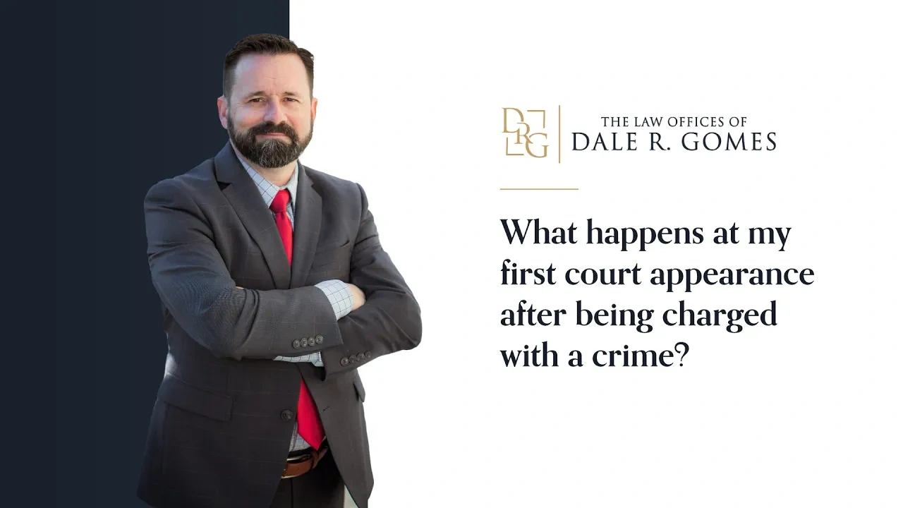 A man in a suit stands with arms crossed next to text that reads, "What happens at my first court appearance after being charged with a crime?" and "The Law Offices of Dale R. Gomes.