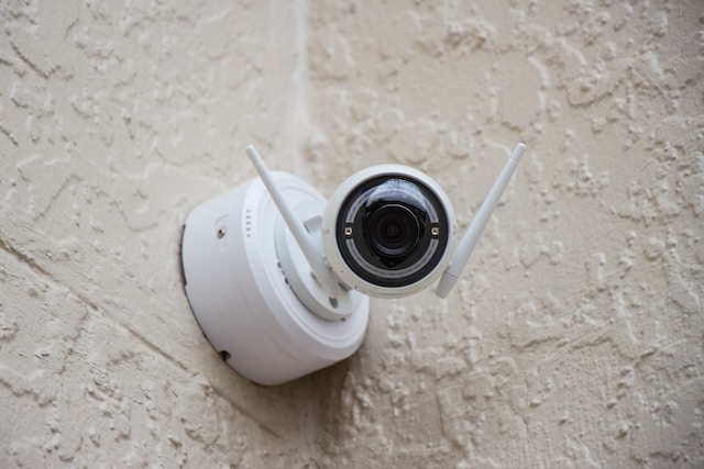 A white security camera with antennas is mounted on a textured beige wall, facing outward—similar to how experts monitor for common symptoms after a car crash, like vigilance for concussion symptoms.