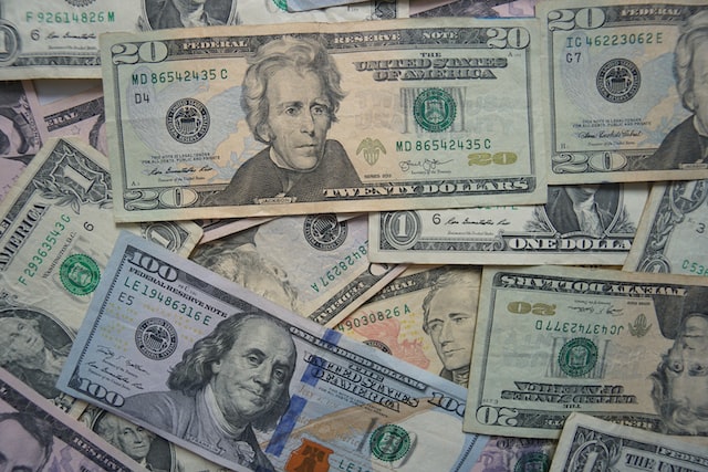 A pile of assorted U.S. dollar bills, including common $1, $5, $10, $20, $50, and $100 denominations, spread out and overlapping each other.