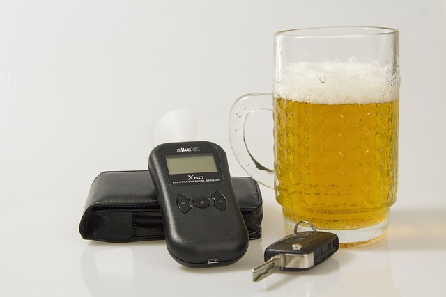 A glass of beer, a breathalyzer, a car key, and a wallet are arranged on a white surface, symbolizing California's ignition interlock requirements for drivers using ignition interlock devices.