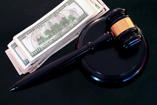 A judge's gavel rests on a sound block next to a stack of U.S. hundred-dollar bills, hinting at the high costs of a California DUI, even if it involves a self-driving car.