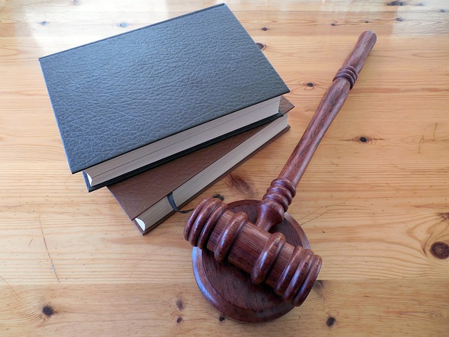 A wooden gavel and three stacked hardcover books rest on a wooden table, symbolizing the legal authority behind California's required Ignition Interlock Devices.