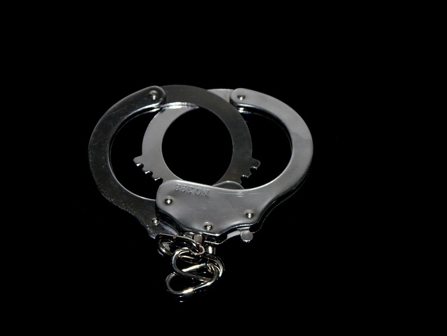 A pair of metal handcuffs is displayed against a black background, evoking thoughts of legal matters like compensation after a slip and fall in a rented apartment.