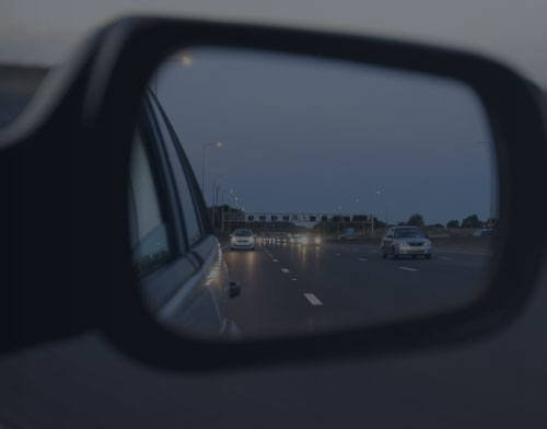 View of cars driving on a multi-lane highway at dusk, seen through a car's side mirror—a reminder that understanding California DUI laws is crucial for all drivers.