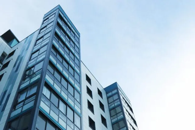 Tall modern apartment building with glass windows set against a clear blue sky, viewed from a low angle—an ideal setting to discuss tenant rights California residents should know.