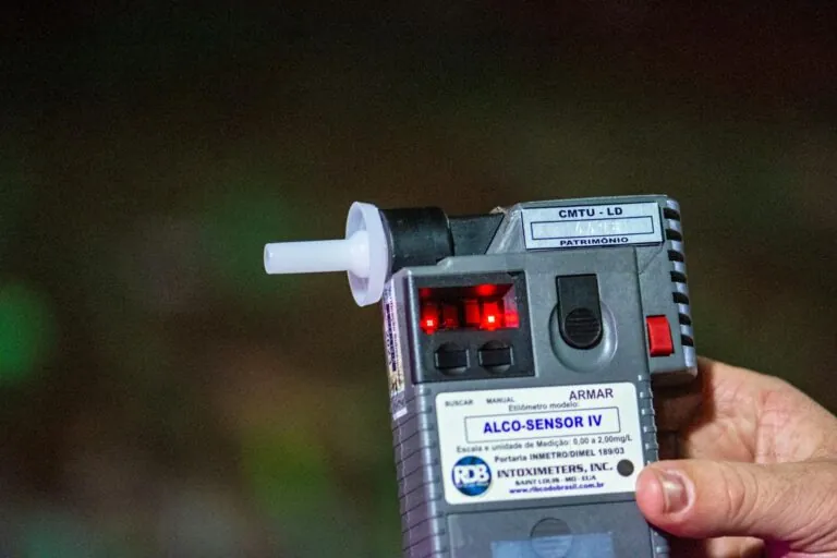 A close-up of a person holding an Alco-Sensor IV breathalyzer device, showing its digital display and mouthpiece, highlights the impact such tools can have on injury claim investigations.