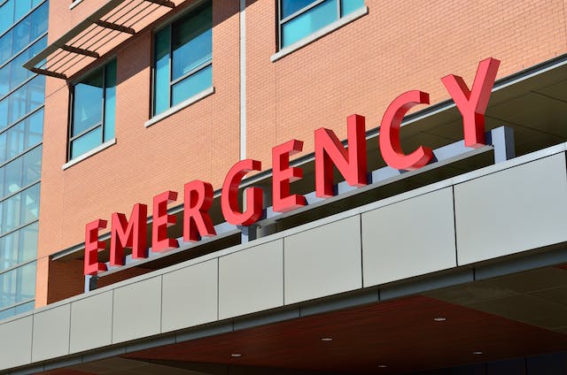 Red "EMERGENCY" sign above the entrance of a hospital building with windows and brick exterior visible—a setting often central to premises liability claims and considerations like the statute of limitations in California.