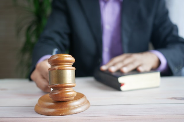 A person in a suit holds a book and sits at a desk with a wooden gavel in the foreground, suggesting an important Decision related to California Workers’ Compensation.