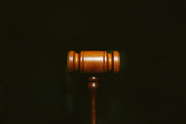 A wooden judge's gavel is centered against a dark background, evoking the seriousness of a California legal dispute.